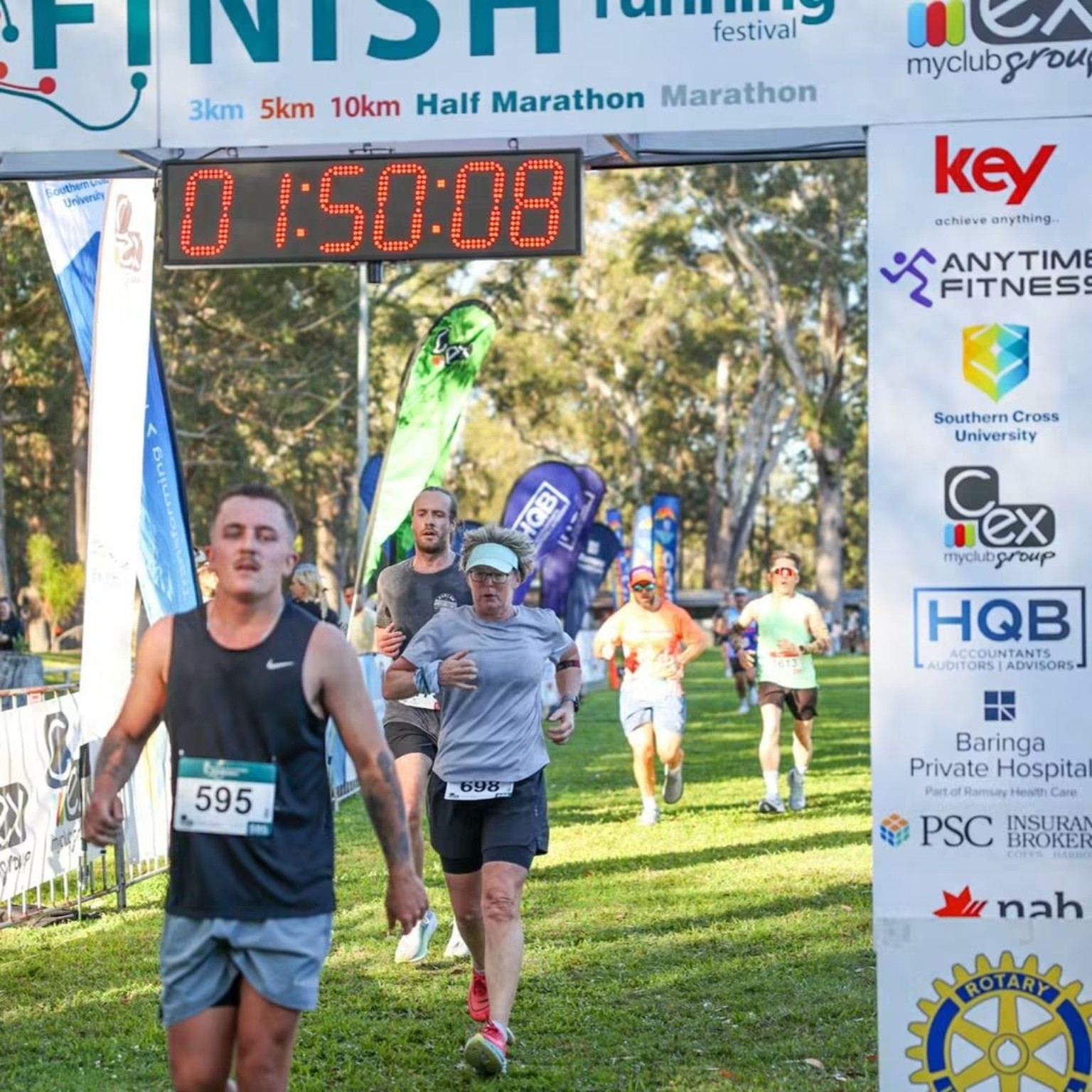Runners crossing beneath the Coffs Harbour Running Festival finish arch.